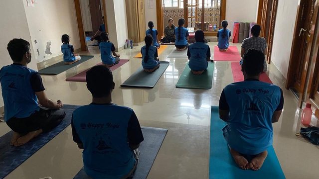 Adults and children seated in meditation facing their teacher at Happy Yogis