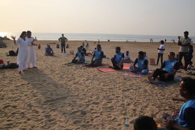 Men from the centre seated on their mats at the beach session at sunset