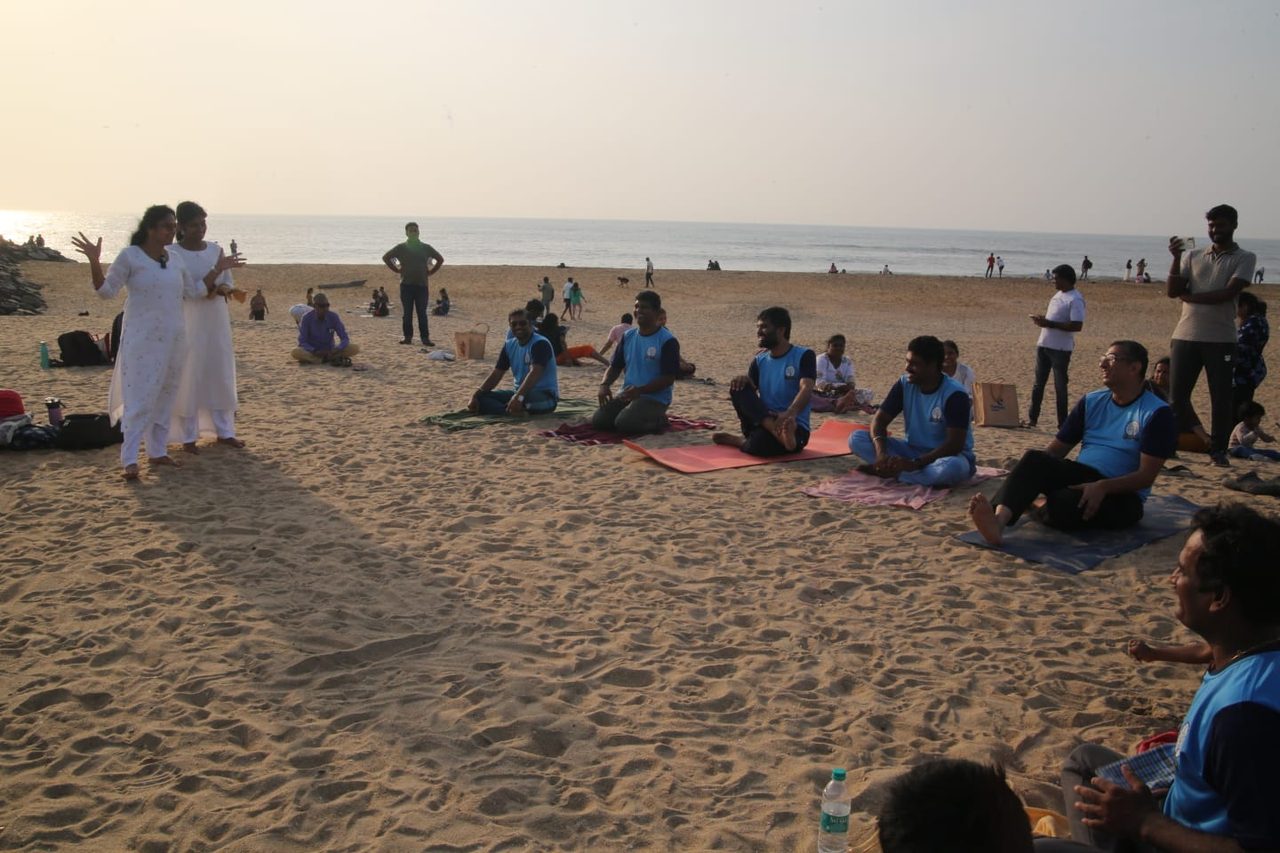 Men from the centre seated on their mats at the beach session at sunset