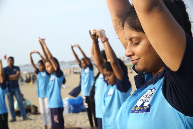 A student stretching both arms overhead in the morning light at the beach
