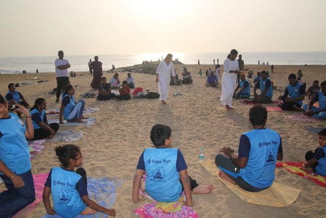 The group seated on mats as the sun comes up over the water