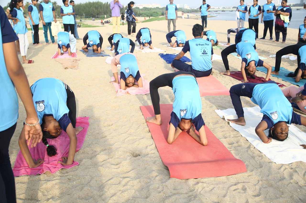 The group holding a standing forward bend on the beach
