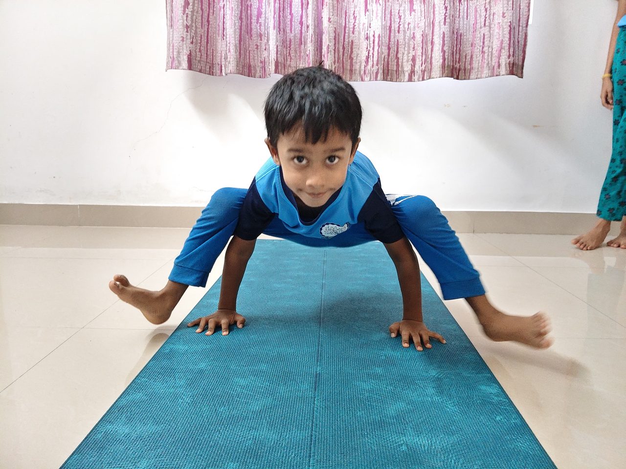 A young boy balancing on his hands in a wide-legged arm balance