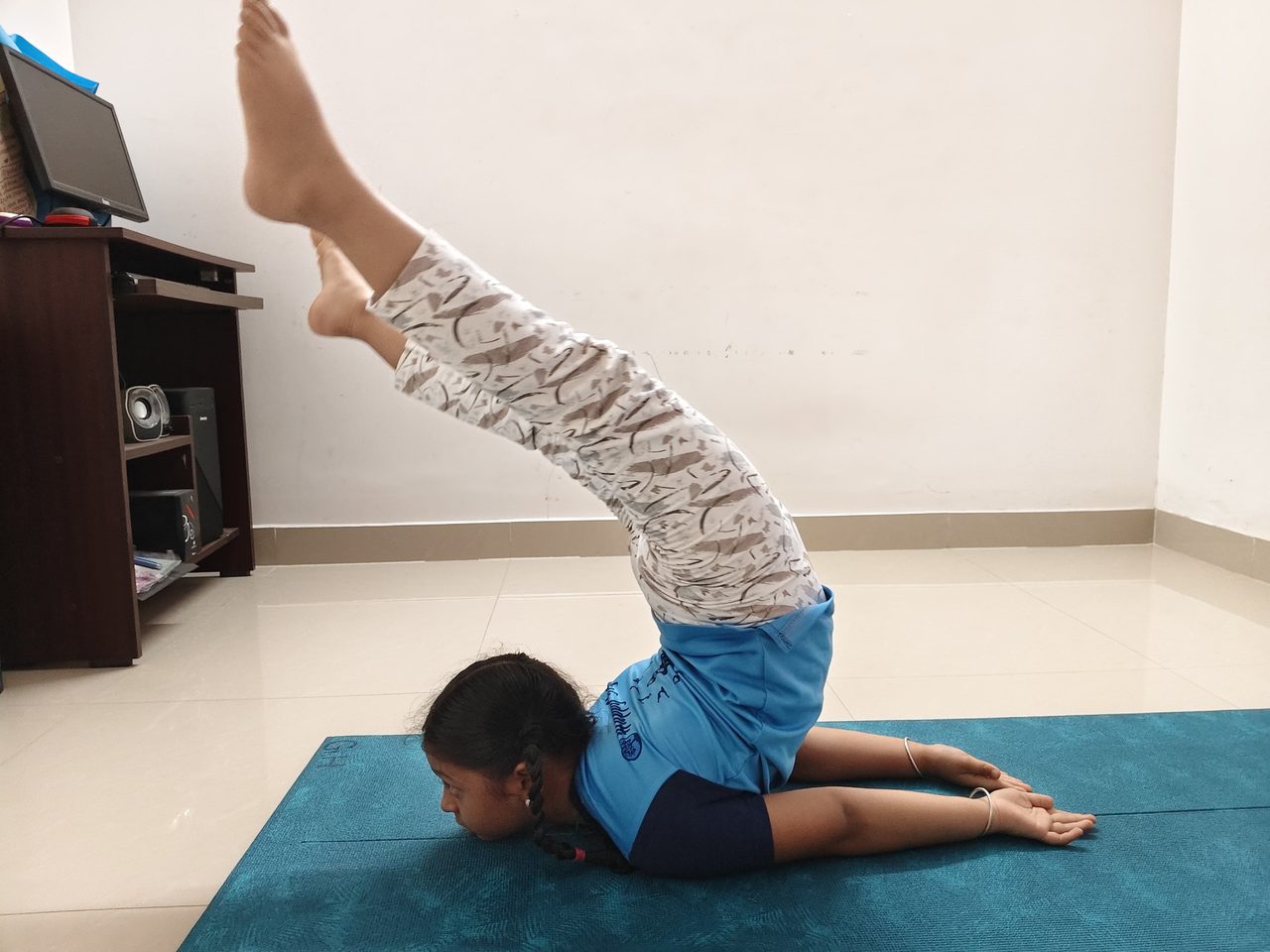 A student holding an inverted shoulder-supported pose, legs overhead