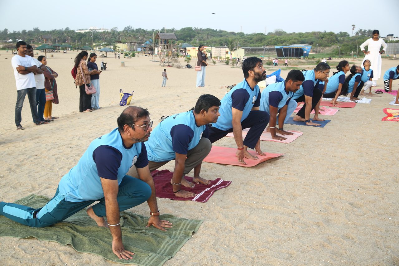 A row of students holding the lunge of a sun salutation on the sand