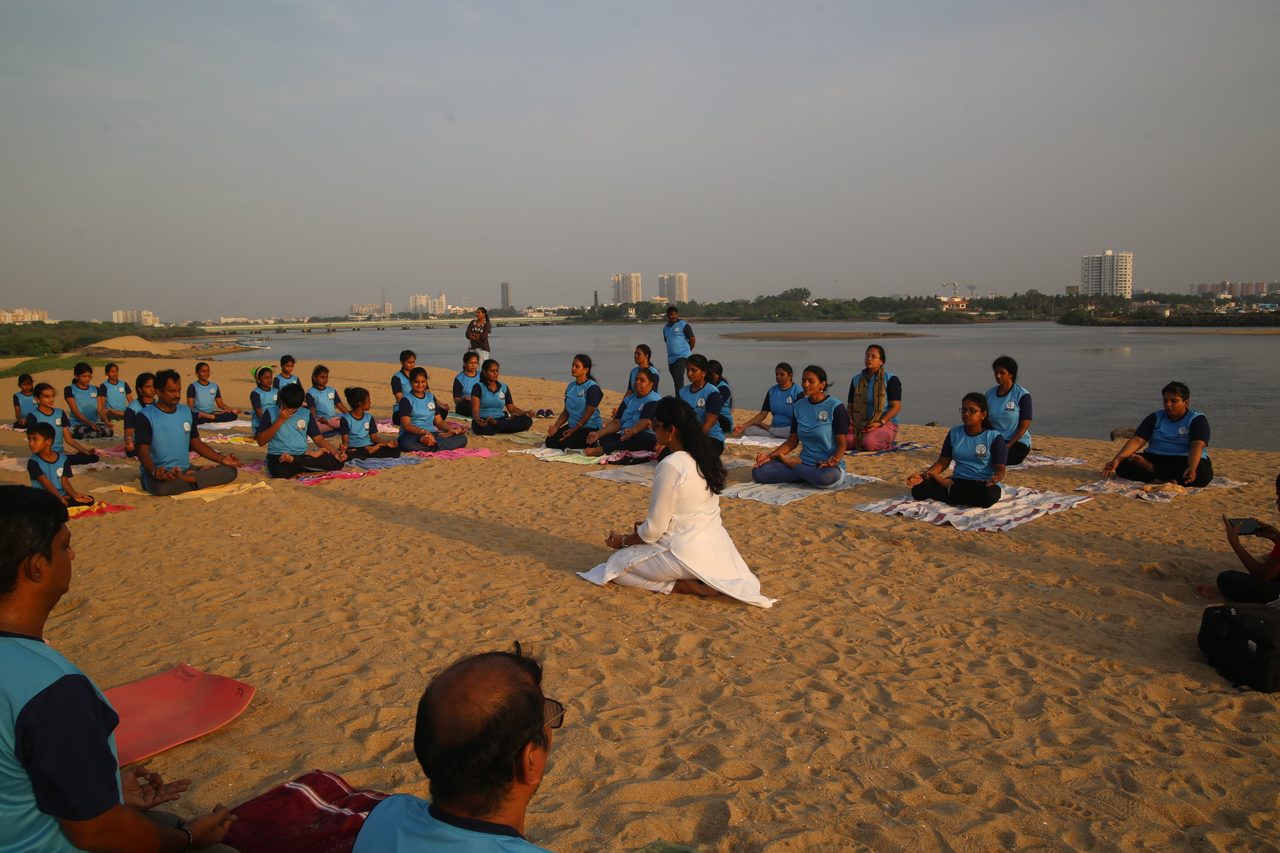The whole group seated for the opening of the morning, water behind