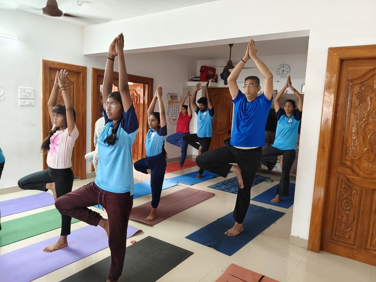 Students of all ages holding tree pose together